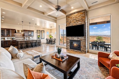 A spacious living area with a fireplace, a large TV, and a view of the desert.