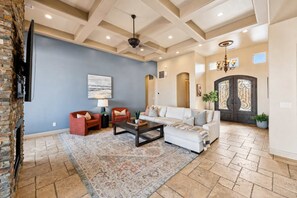 A spacious living room with a fireplace, a sofa, two armchairs, a coffee table, and a patterned rug.