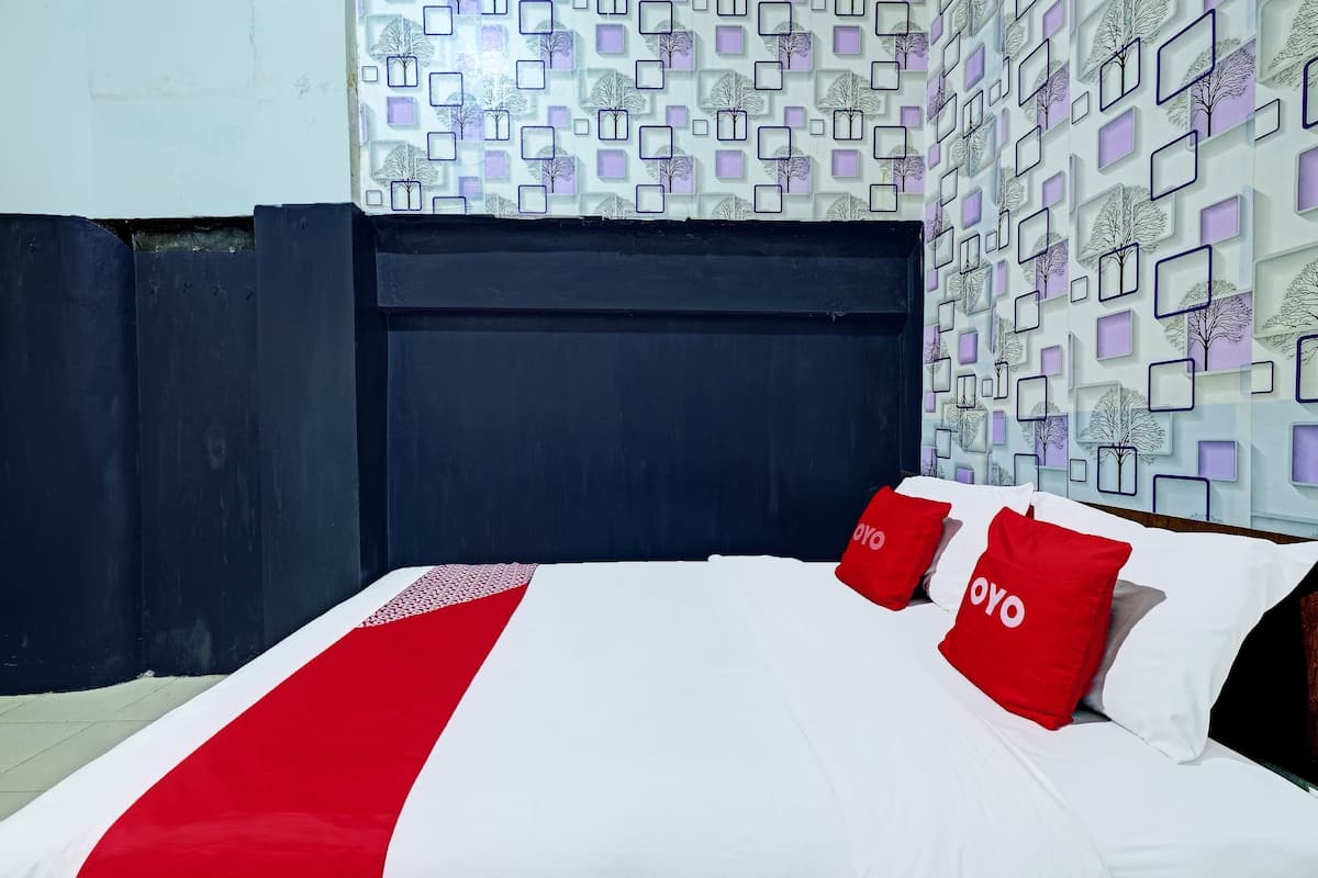 Ein Hotelzimmer mit einem Bett, einem Kopfteil und einer Wand mit Muster.