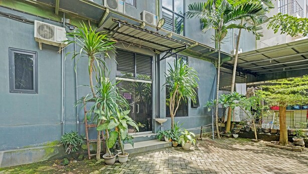 A courtyard with potted plants, a metal staircase, and a building with air conditioning units. - OYO Life 2928 Rumah Ceria (Semarang)