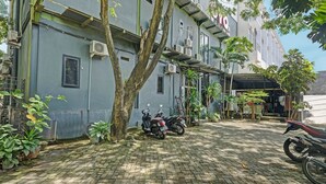 A paved courtyard with two motorcycles parked, surrounded by a building with air conditioning units and a covered area with plants. - OYO Life 2928 Rumah Ceria (Semarang)