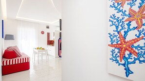 Ein modernes Wohnzimmer mit einem roten Sofa, einem weißen Esstisch und einer Küche im Hintergrund.