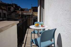 A balcony with a table and chairs, a plate with fruits, and a glass of drink. - Modern Apartment with a Bathtub in the City Center – A Quiet Retreat Near Downtown (Sorrento)