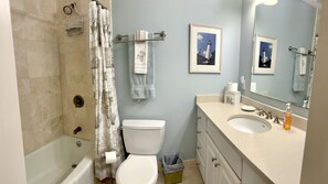A bathroom with a bathtub, toilet, sink, and a shower curtain. - L3, downstairs Oceanwalk/remodeled (St. Simons Island)