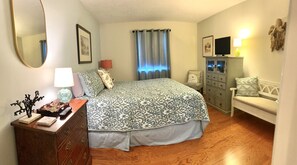 A bedroom with a bed, dresser, nightstand, and a television on a cabinet. - L3, downstairs Oceanwalk/remodeled (St. Simons Island)
