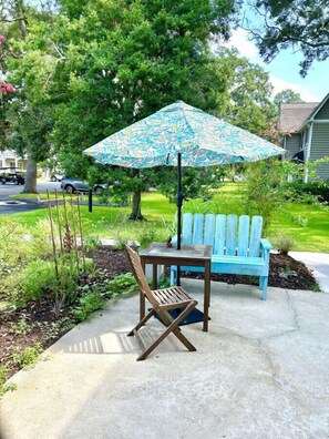 A patio with a blue bench, a wooden chair, and a patterned umbrella. - O1 Two BR townhome in Ocean Walk with 1 king, 1 queen bed.  Recently updated. (Saint Simons Island)