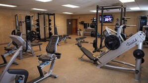 A gym with various exercise equipment, including treadmills, weight machines, and a television on the wall. - Target Hospitality-Cheecham Lodge (Janvier South)