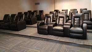 A conference room with rows of black leather chairs, carpeted flooring, and a plain wall with a vent. - Target Hospitality-Cheecham Lodge (Janvier South)