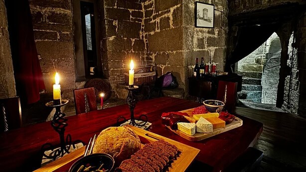 A rustic dining room with stone walls, a wooden table set with food, and candles. - Ballindooley Castle 10 minutes to Galway City (Galway)