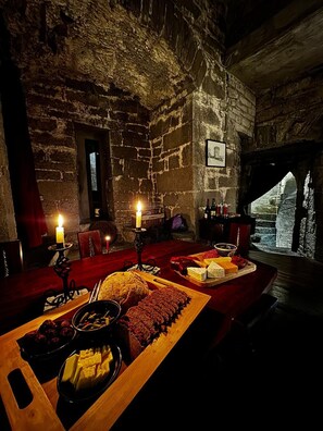 A rustic dining room with stone walls, a wooden table set with food, and candles. - Ballindooley Castle 10 minutes to Galway City (Galway)