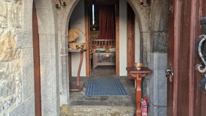A stone-walled hallway with a wooden door, a small table with a bowl, and a patterned rug on the floor. - Ballindooley Castle 10 minutes to Galway City (Galway)