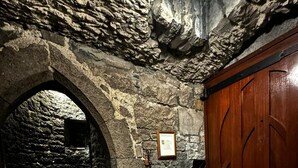 A stone-walled room with a wooden door and an arched doorway leading to a staircase. - Ballindooley Castle 10 minutes to Galway City (Galway)