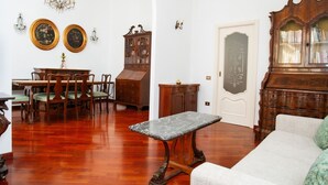 A traditional room with a wooden dining table, chairs, a marble coffee table, a sofa, and a large wooden cabinet.