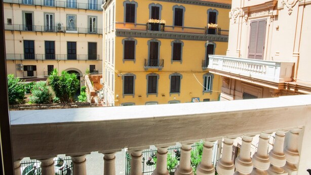 A balcony with a view of a yellow building with multiple windows and balconies.