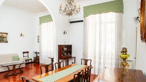 A dining room with a wooden table, chairs, a chandelier, and a green patterned runner.