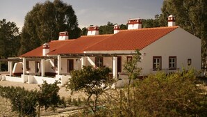 A white building with a red-tiled roof, multiple chimneys, and a covered porch area. - Partridge House (Coruche)