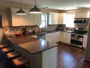 Kitchen features a central island with sink and dishwasher, classic cabinetry, and stainless steel appliances.