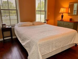 Relax in this serene bedroom with a large bed, bedside table, and a dresser.