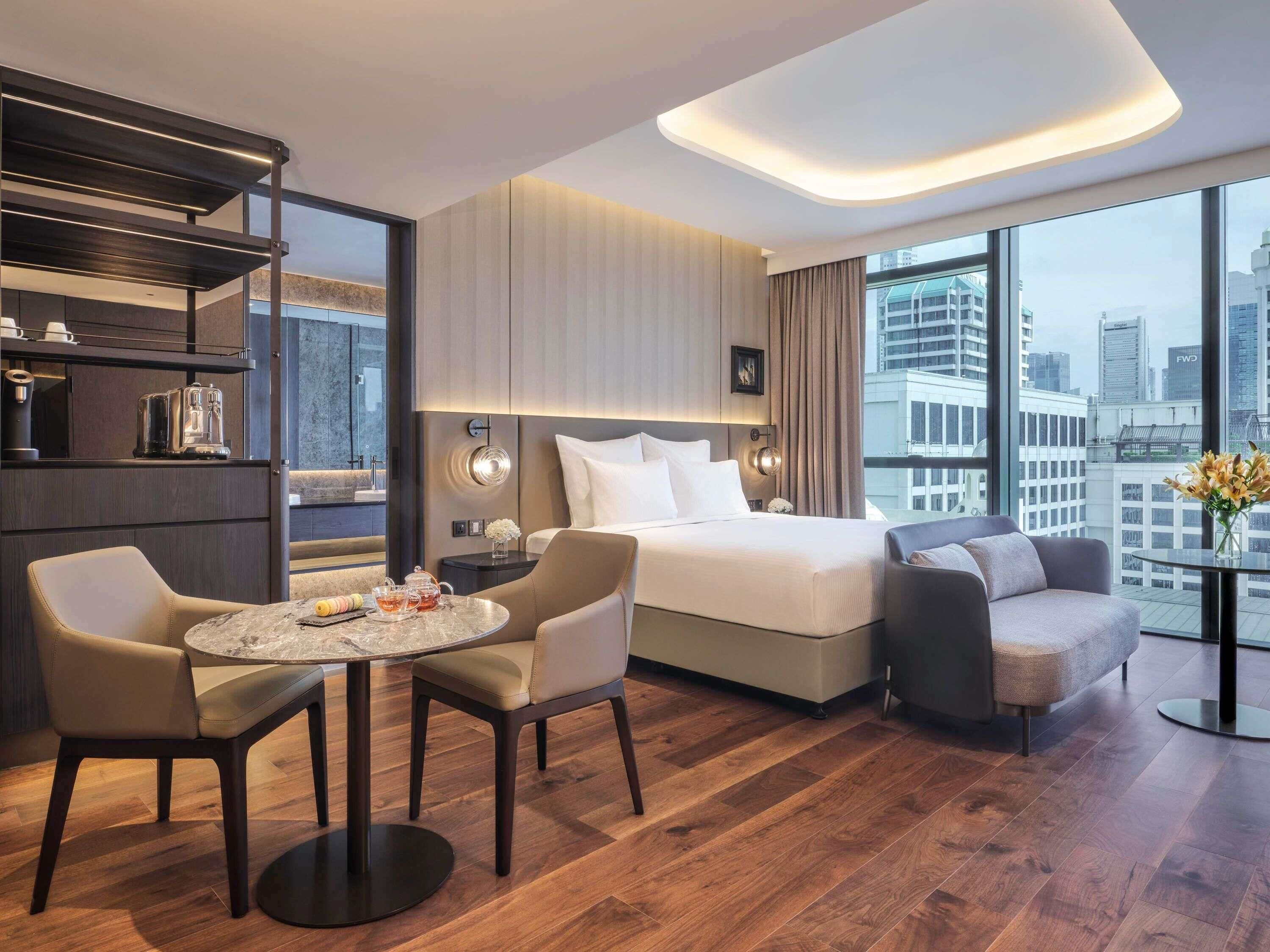 Una habitación de hotel moderna con cama, zona de estar y vistas a la ciudad.