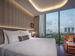 Une chambre d’hôtel moderne avec un grand lit, un bureau avec une chaise et une vue sur les bâtiments de la ville.