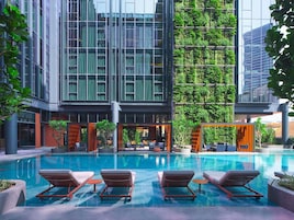 A modern building with a glass facade, a rooftop garden, and a swimming pool with lounge chairs.