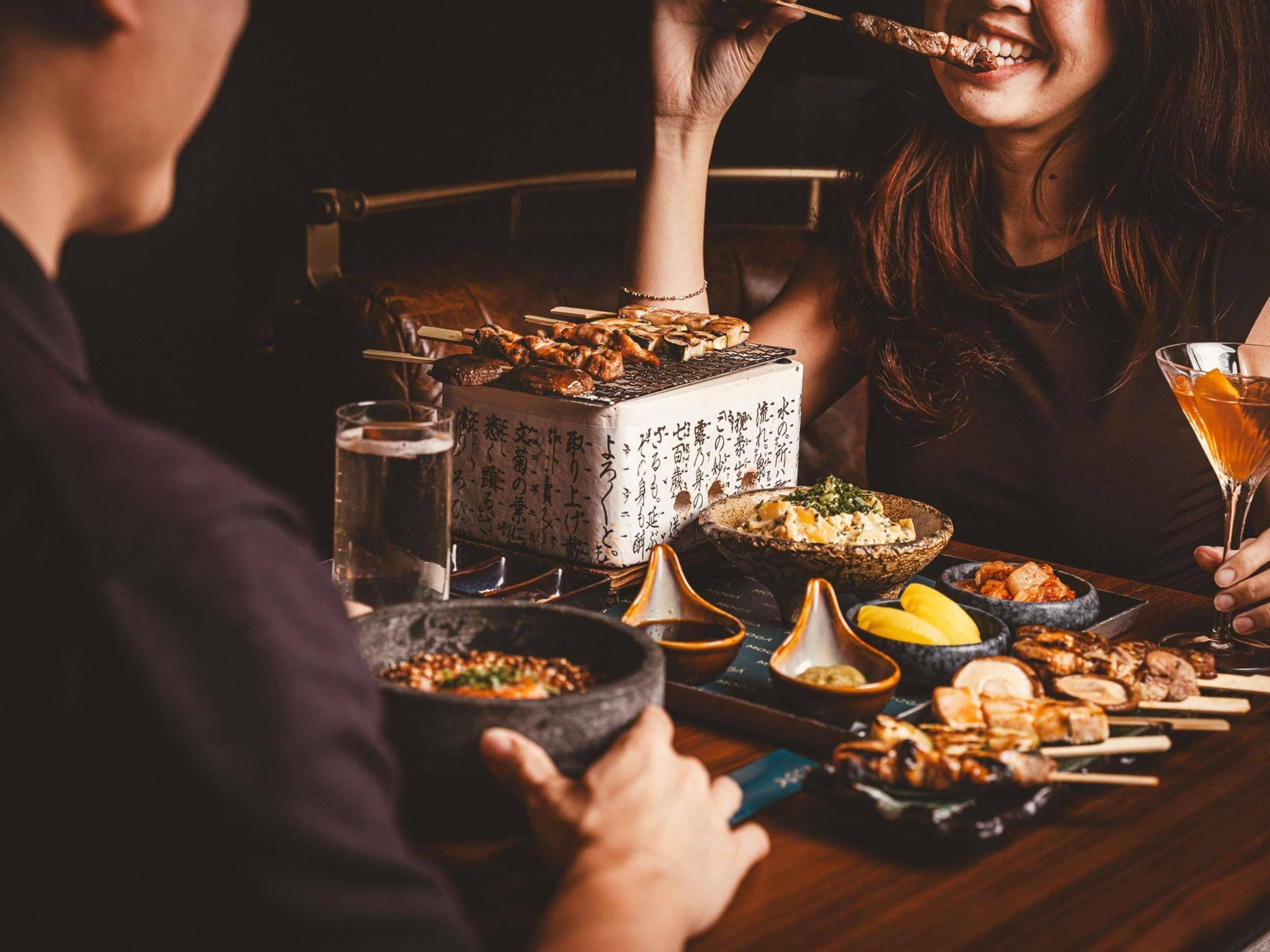 A dining table with various dishes, including skewers and bowls, and a drink in a martini glass.