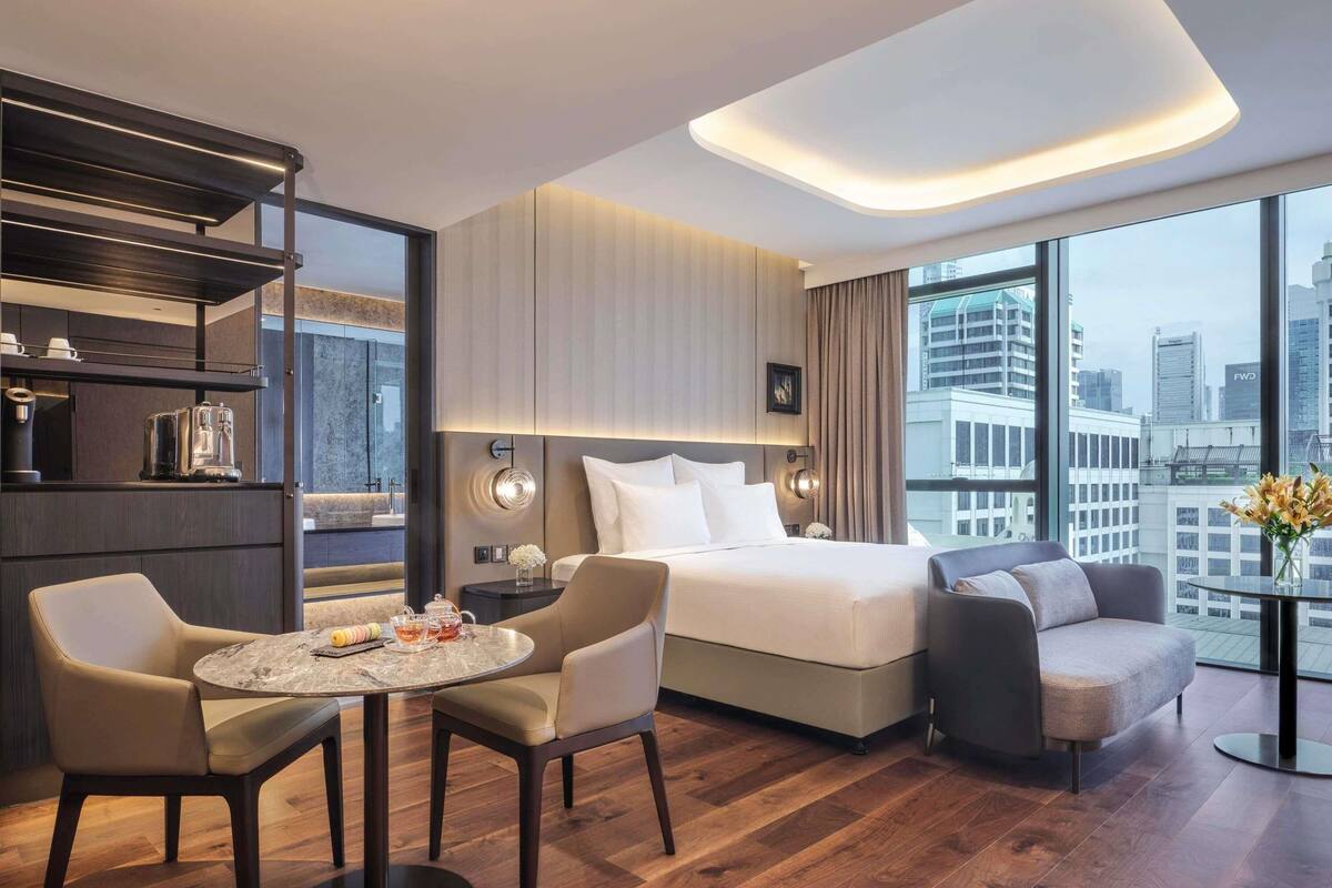 Une chambre d’hôtel moderne dotée d’un lit, d’un coin salon et offrant une vue sur la ville.