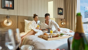 A hotel room with a bed, breakfast tray, and a bottle of champagne. - Pullman Singapore Hill Street (Singapore)