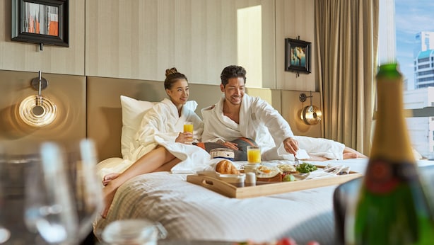 A hotel room with a bed, breakfast tray, and a bottle of champagne. - Pullman Singapore Hill Street (Singapore)