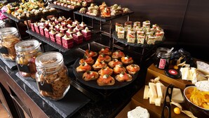 A buffet with various food items including sandwiches, pastries, and cheese. - Pullman Singapore Hill Street (Singapore)