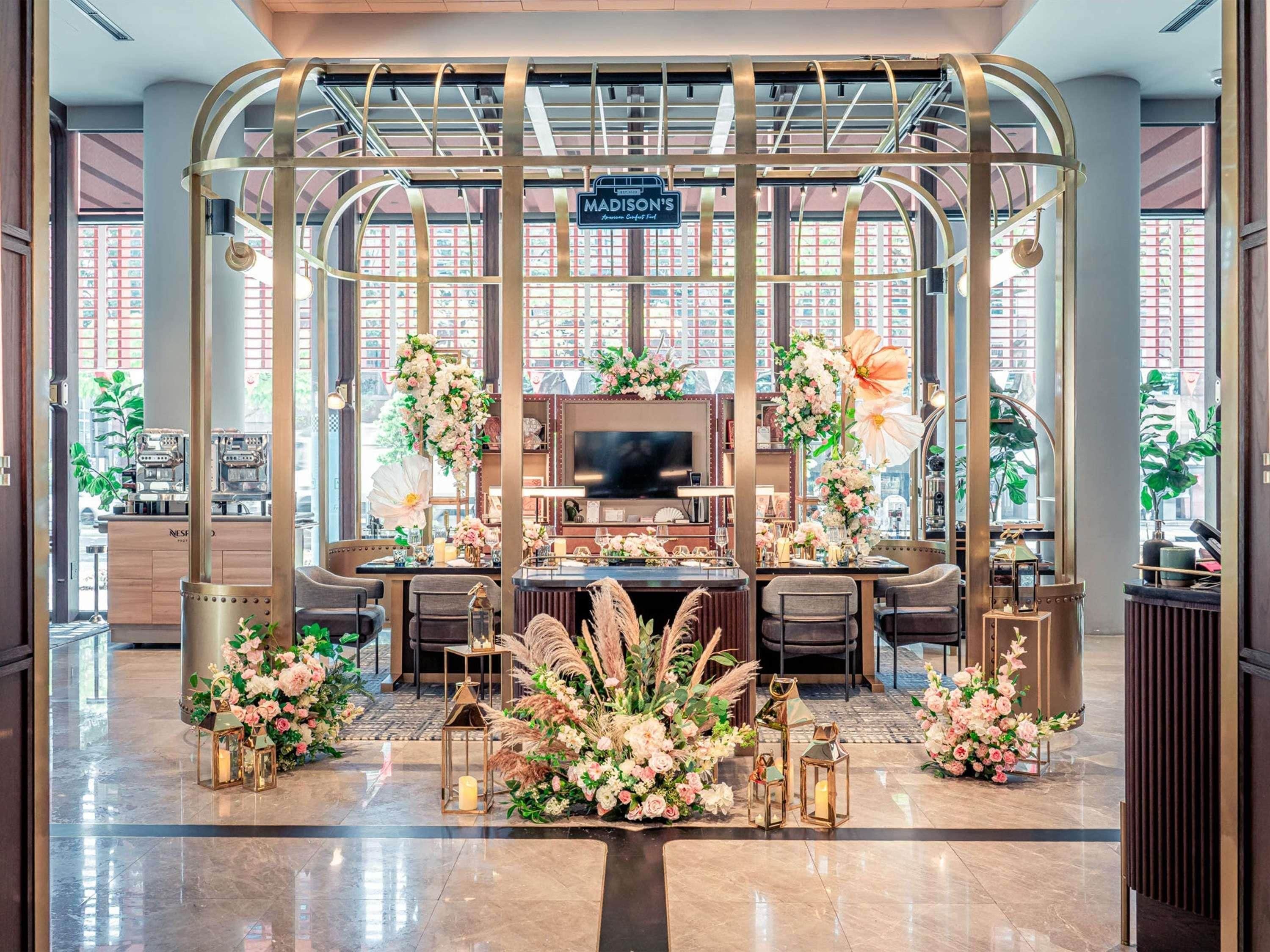 Un área de recepción con diseño moderno, que incluye un mostrador central, zona de estar y arreglos florales decorativos.