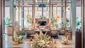 Un área de recepción con diseño moderno, que incluye un mostrador central, zona de estar y arreglos florales decorativos.