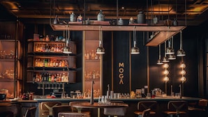 A bar area with a dark interior, wooden shelves with bottles, and hanging pendant lights. - Pullman Singapore Hill Street (Singapore)