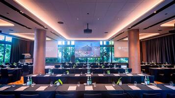 A conference room with tables set for a meeting, large windows with a cityscape view, and a presentation screen.