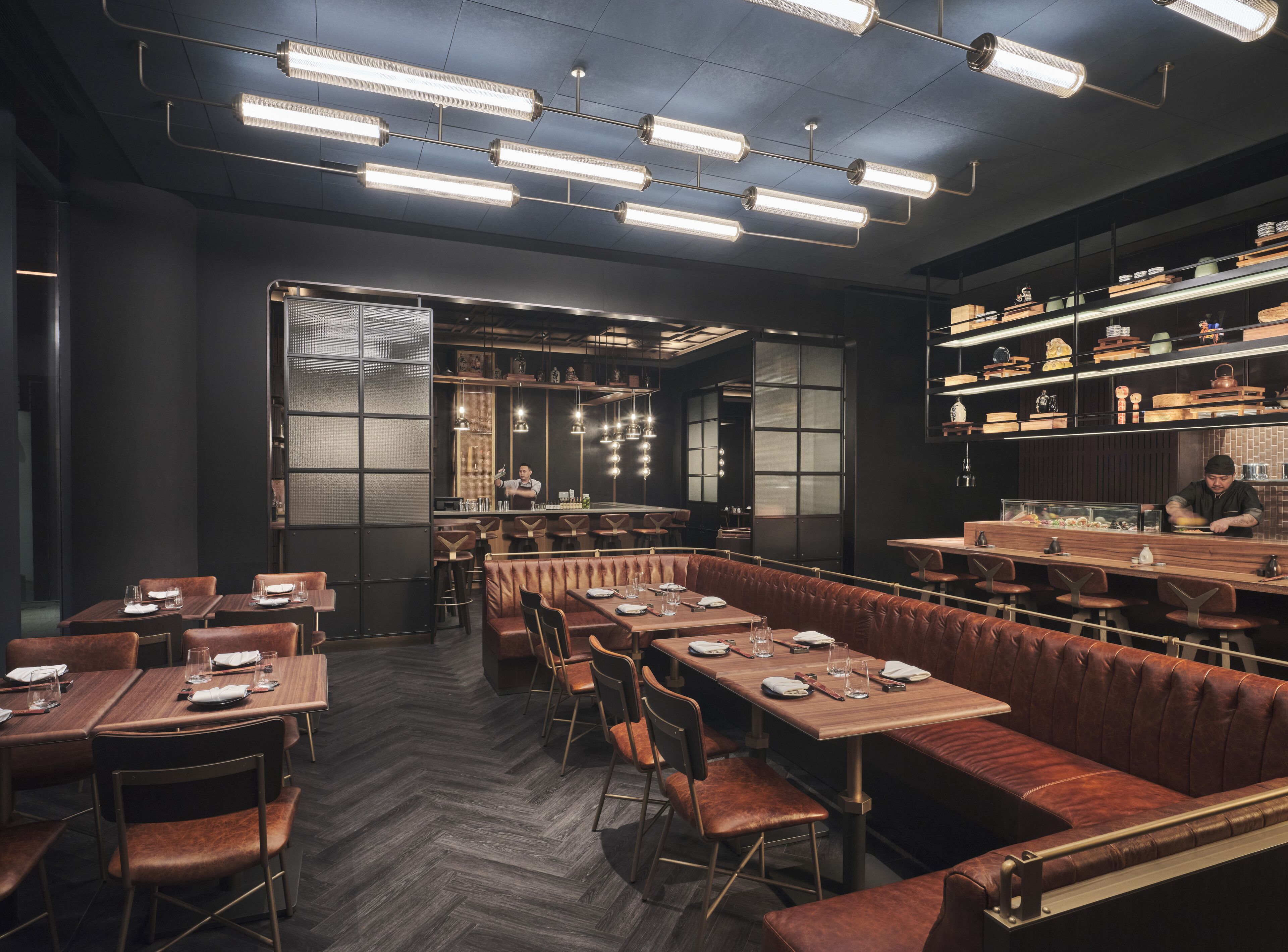 A modern restaurant with a long counter, booths, and a bar area.
