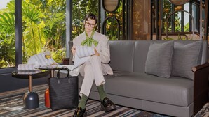 A person seated on a grey sofa with a view of lush greenery through large windows. - Pullman Singapore Hill Street (Singapore)