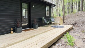 A cabin with a wooden deck, two chairs, a small table, and a window. - Mossy Moody Cabin in High Falls, NY (High Falls)