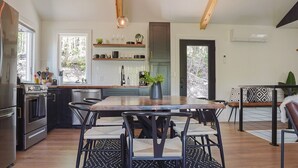 A modern kitchen with a central island, stainless steel appliances, and a dining area with a wooden table and chairs. - Mossy Moody Cabin in High Falls, NY (High Falls)