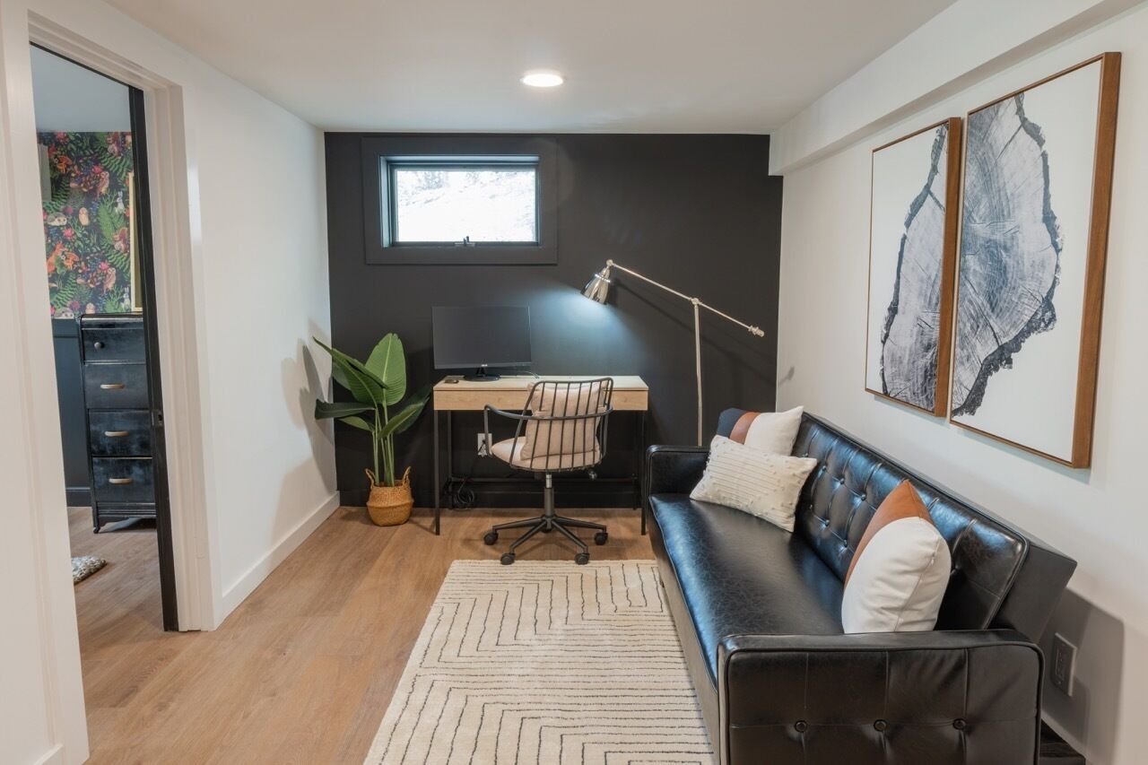 A modern room with a desk, chair, and sofa.