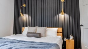 A modern bedroom with a dark wooden slat wall, a wooden headboard, and two gold bedside lamps. - Mossy Moody Cabin in High Falls, NY (High Falls)