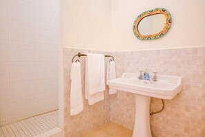 Een badkamer met een wit wastafelmeubel, een spiegel met decoratieve lijst en een handdoekrek met witte handdoeken.