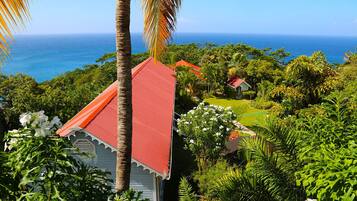 A coastal property with a red-roofed building surrounded by lush greenery and a view of the ocean.