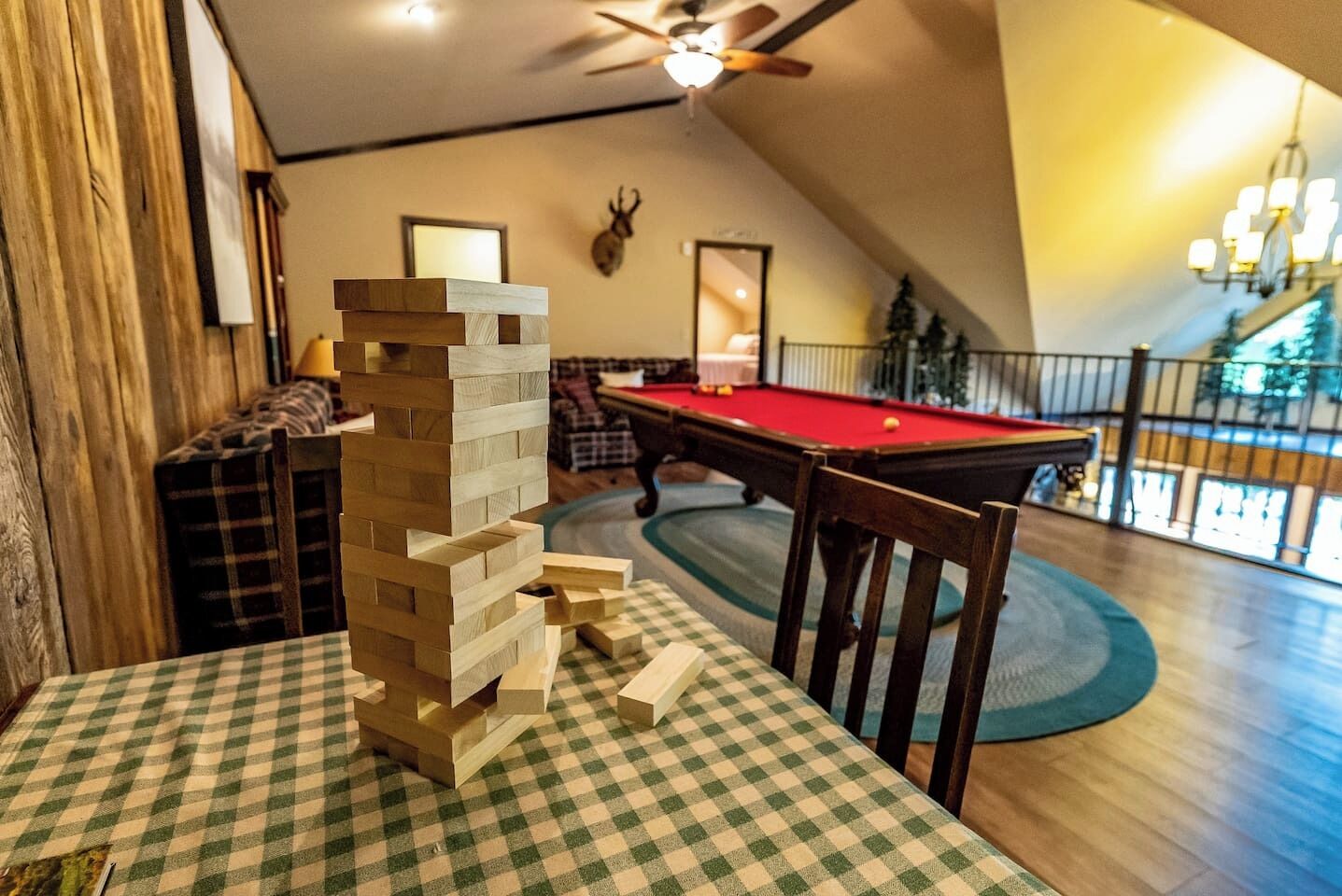 Una mesa de billar en una habitación con techo alto y una estructura de madera que recuerda a una torre de Jenga.