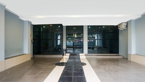 Une entrée moderne, avec des portes en verre et un sol carrelé.