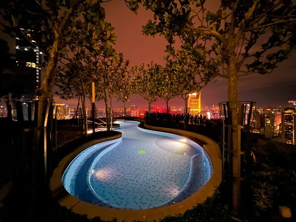 A nighttime swimming pool with a cityscape view in the background.