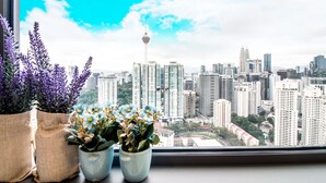 Une vue urbaine avec une tour imposante, des immeubles de grande hauteur et des plantes en pot sur un rebord de fenêtre.