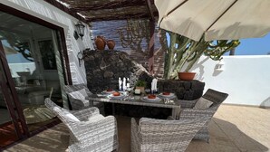 Eine Terrasse im Freien mit Korbmöbeln, einer Steinmauer und Blumentöpfen.