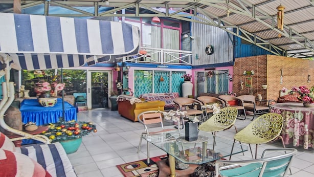 A spacious indoor area with a high ceiling, a striped awning, and various seating arrangements including chairs and sofas. - SPOT ON 92278 Hotel Vorel (Tondano)