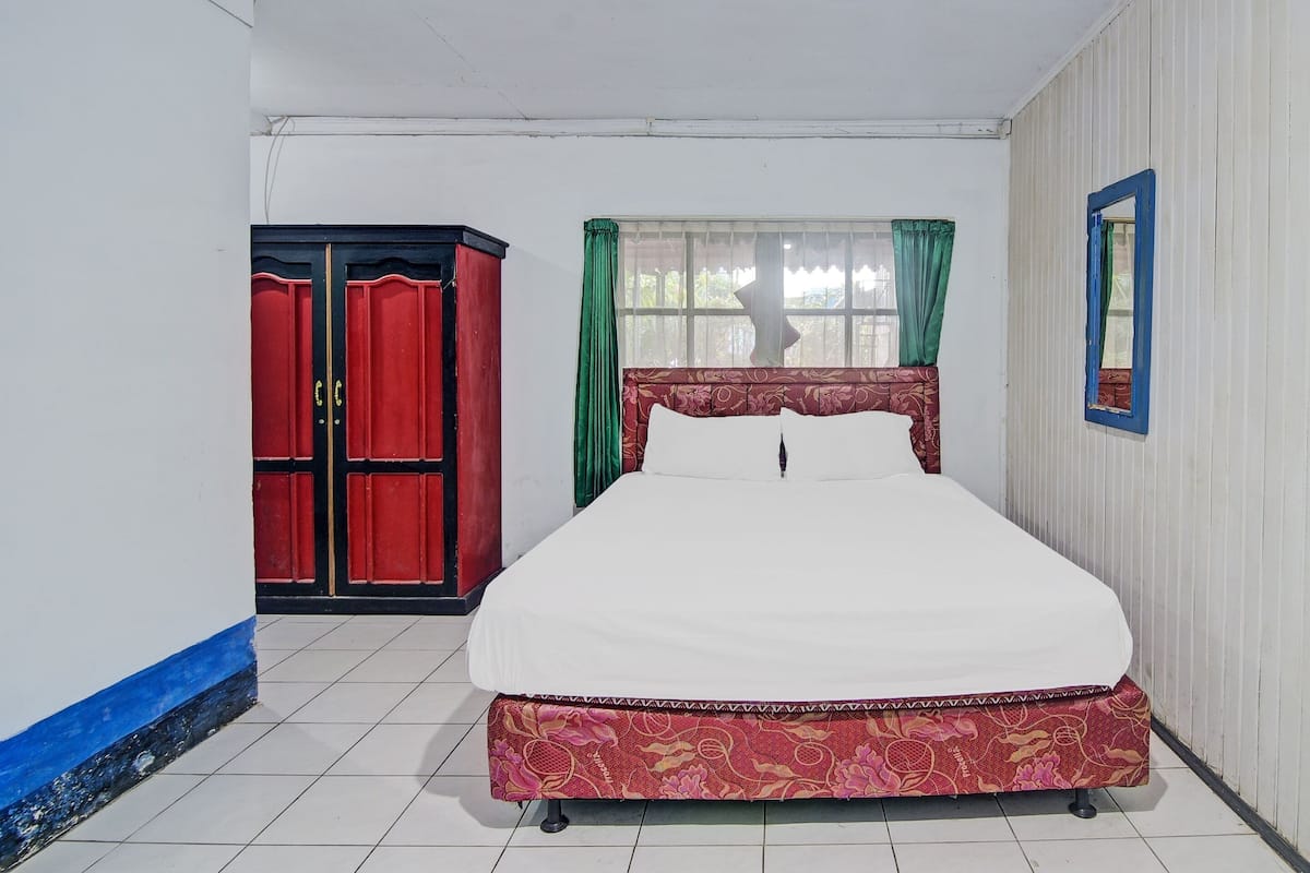 Une pièce comprenant un lit, une armoire, une fenêtre avec des rideaux et un miroir.