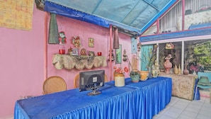 A reception area with a blue table, wicker chairs, and a computer monitor. - SPOT ON 92278 Hotel Vorel (Tondano)
